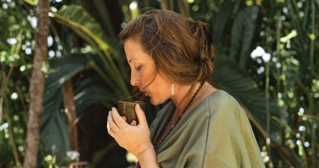 Sacred Earth Medicine ceremonial cacao ritual for mums - woman sipping warm cup of cacao in nature