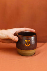 Hand holding a large ceremonial cup, embossed with a real gold lustre Sacred Earth Medicine symbol. The cup is made from wild harvested clay sourced using methods taught by the indigenous people from the Northern Rivers of NSW.