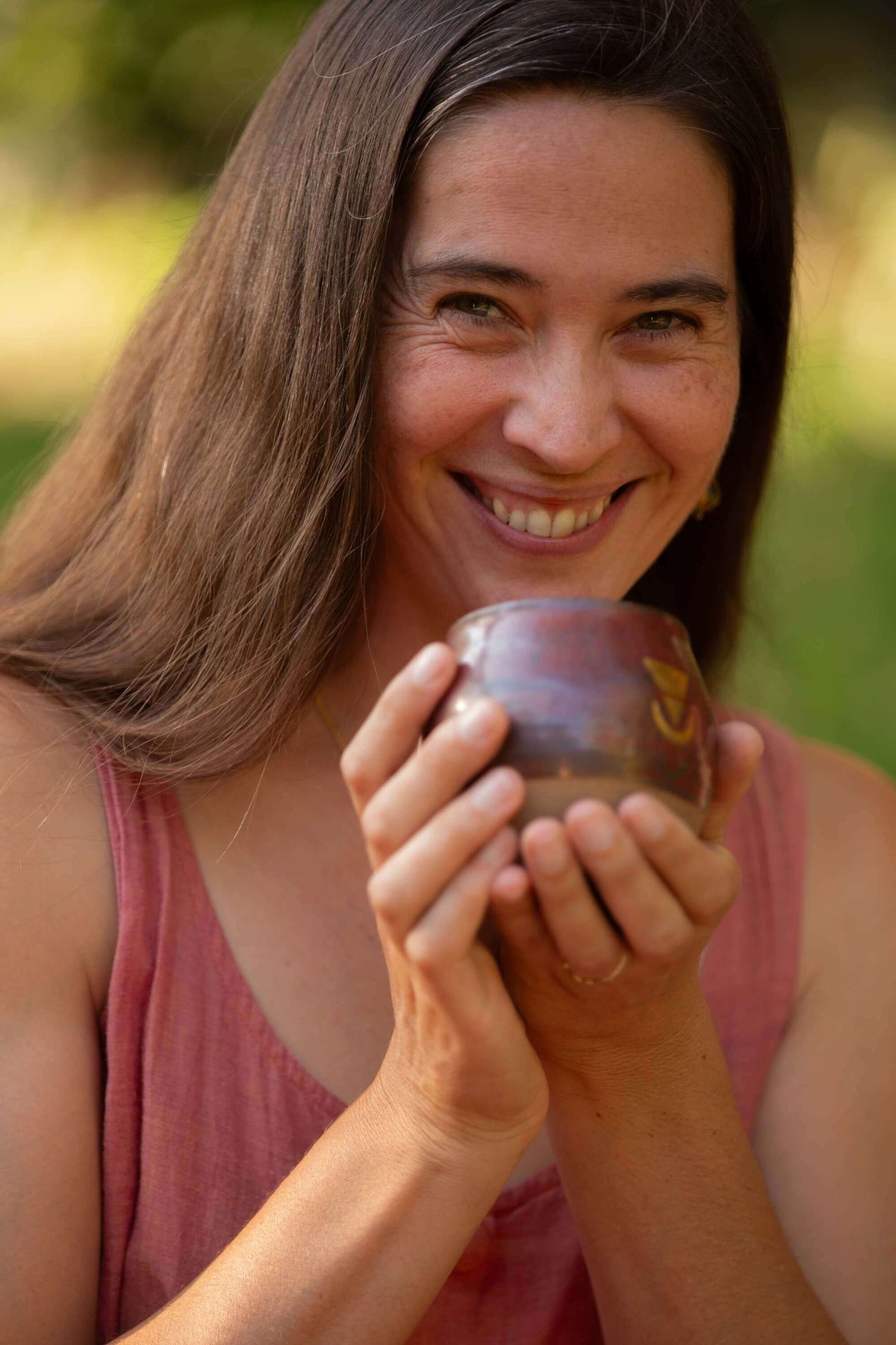 A beautiful woman with a wide open heart and a big smile holding a large size Sacred Earth Medicine cup 